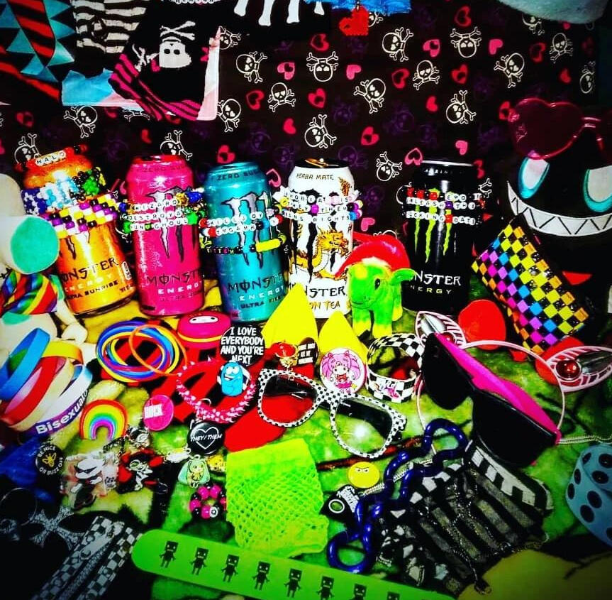 A collection of scene gear, such as sunglasses, kandi bracelets, Monster brand energy drinks, and jelly bracelets.